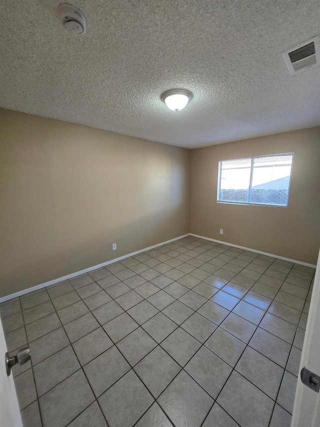 spare room with visible vents, a textured ceiling, baseboards, and light tile patterned flooring