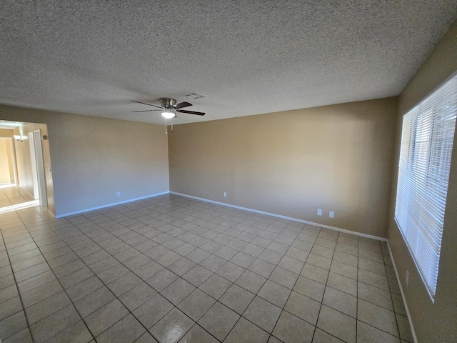 empty room featuring visible vents, ceiling fan, a textured ceiling, baseboards, and tile patterned floors