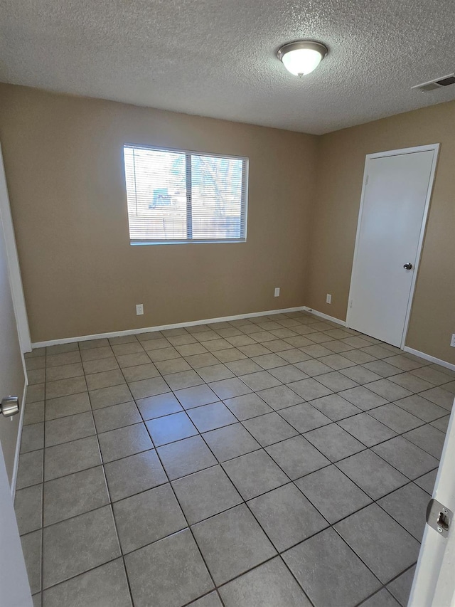 empty room featuring visible vents, baseboards, and a textured ceiling