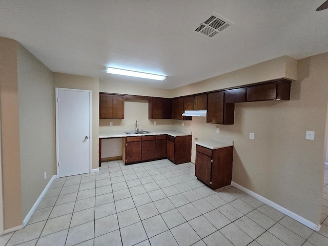 kitchen featuring dark brown cabinetry, visible vents, light countertops, under cabinet range hood, and a sink