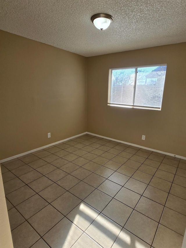 empty room with a textured ceiling and baseboards