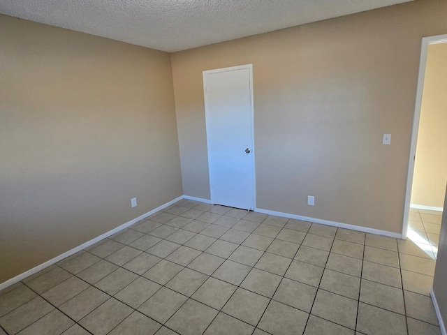 empty room featuring a textured ceiling and baseboards