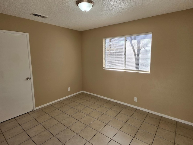 empty room featuring baseboards, visible vents, and a textured ceiling