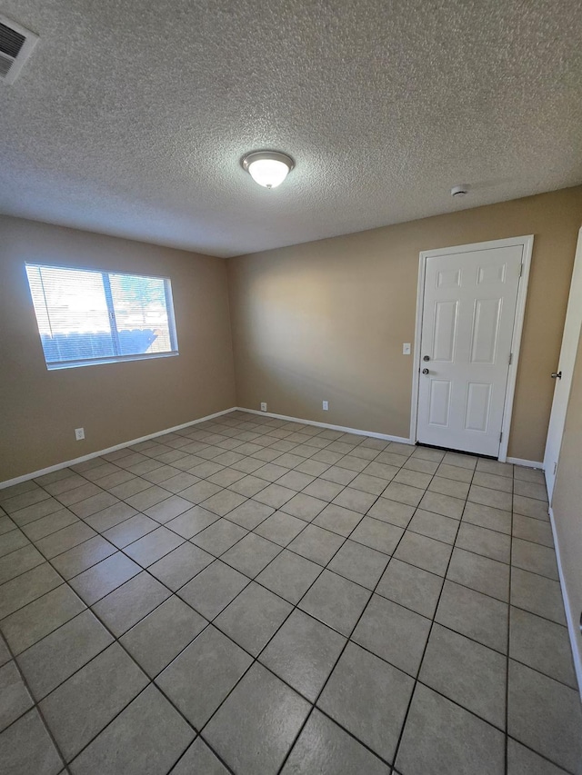 empty room featuring a textured ceiling, visible vents, and baseboards