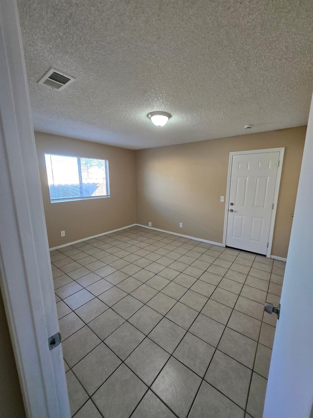 empty room featuring baseboards, visible vents, and a textured ceiling