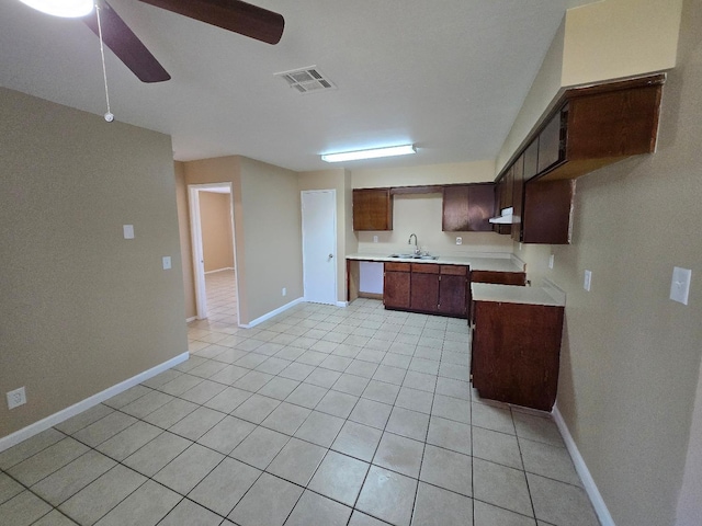 kitchen with light tile patterned floors, a sink, visible vents, baseboards, and light countertops