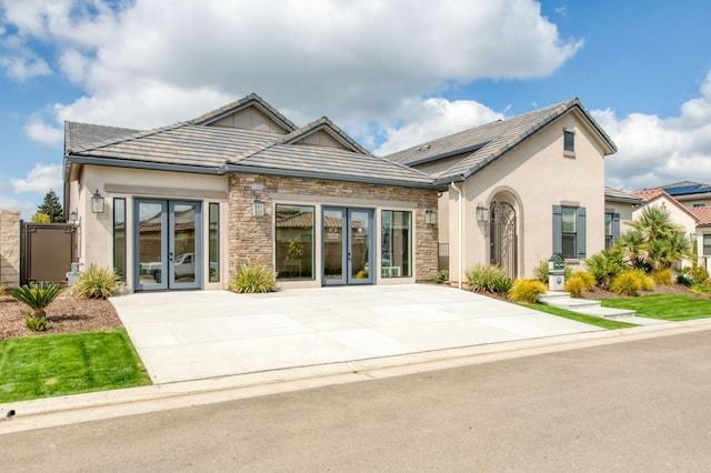 view of front of home featuring stone siding, stucco siding, and french doors