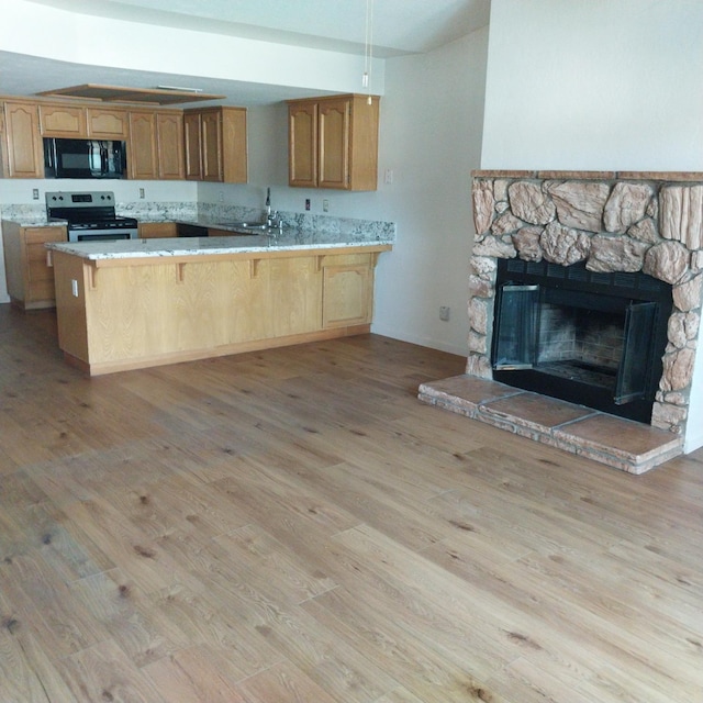 kitchen with light wood-type flooring, stainless steel range with electric stovetop, black microwave, and light countertops