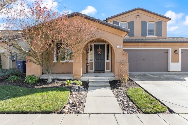 mediterranean / spanish house with driveway, a tiled roof, an attached garage, and stucco siding