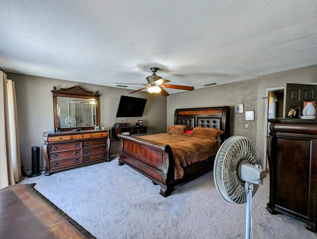 carpeted bedroom with visible vents, ceiling fan, and a textured ceiling