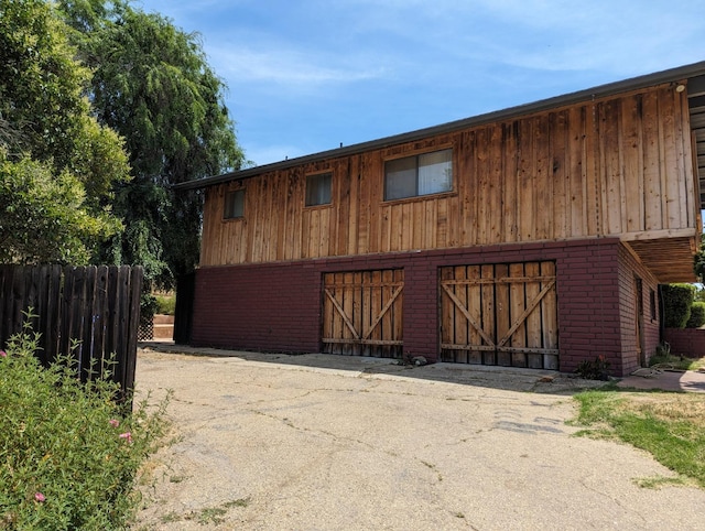 view of front of home featuring a barn, fence, an outbuilding, and brick siding