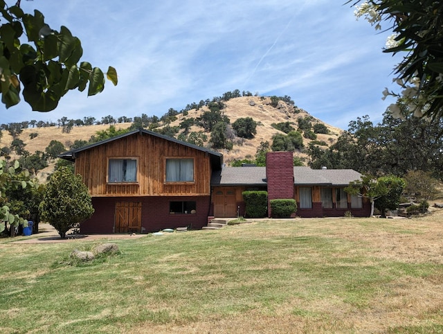 view of front of property with a chimney, a mountain view, a front lawn, and brick siding