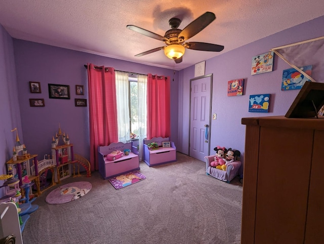 playroom featuring carpet, ceiling fan, and a textured ceiling