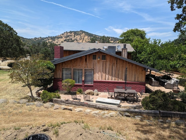 back of house with a patio, a chimney, and a mountain view