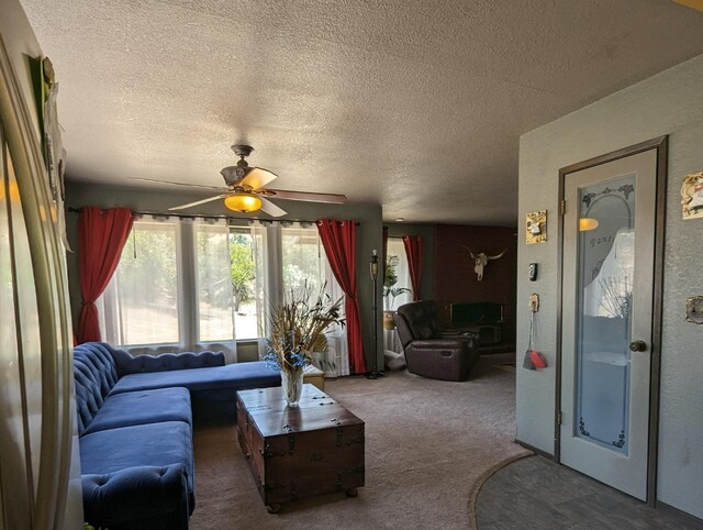 living area featuring carpet floors, a ceiling fan, and a textured ceiling