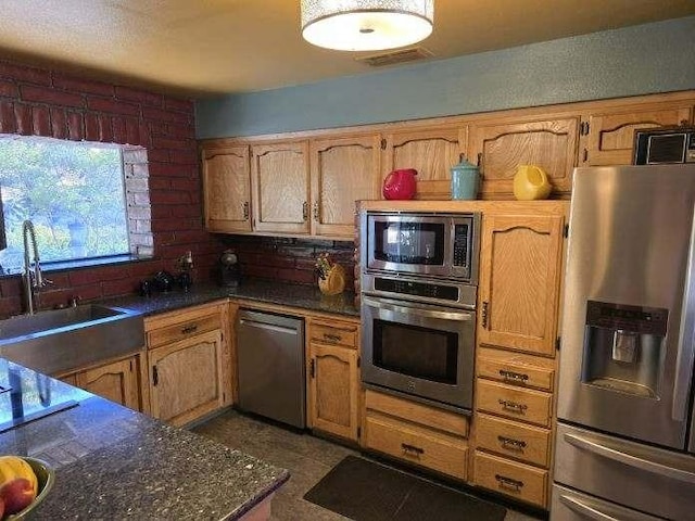 kitchen featuring dark countertops, visible vents, appliances with stainless steel finishes, and a sink