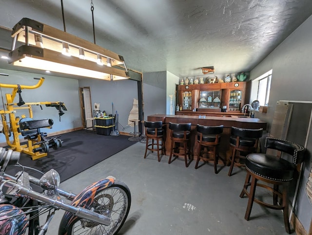 interior space featuring concrete flooring, wet bar, and a textured ceiling