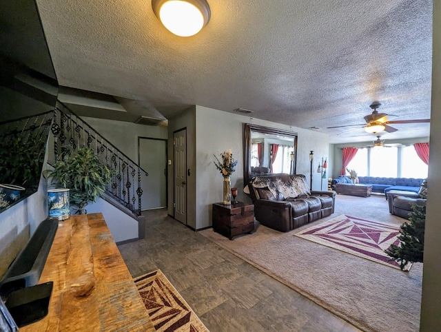 living area featuring visible vents, ceiling fan, a textured ceiling, and stairs