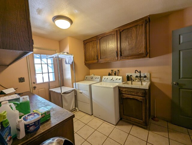 washroom featuring light tile patterned floors, a textured ceiling, a sink, cabinet space, and washing machine and clothes dryer