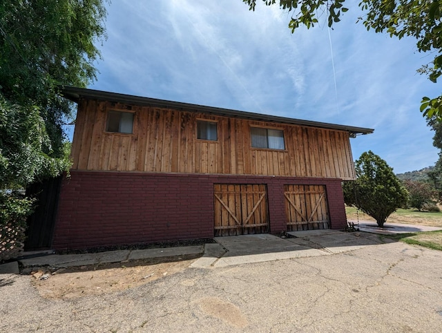 exterior space with a garage, brick siding, an outdoor structure, a barn, and driveway