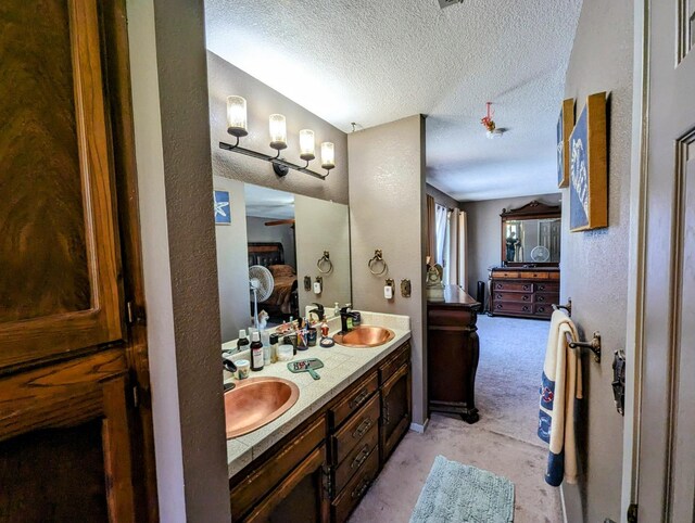 full bathroom featuring a textured ceiling, a textured wall, and a sink