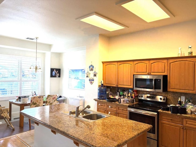 kitchen featuring appliances with stainless steel finishes, backsplash, a sink, and brown cabinetry