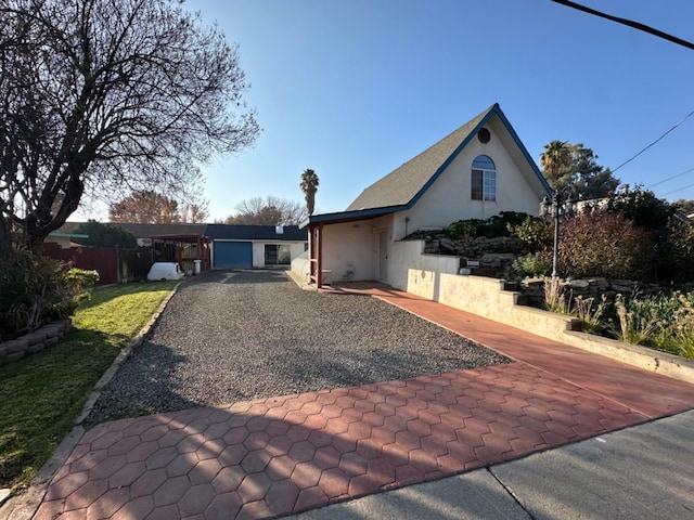 view of front of property featuring gravel driveway, fence, and stucco siding