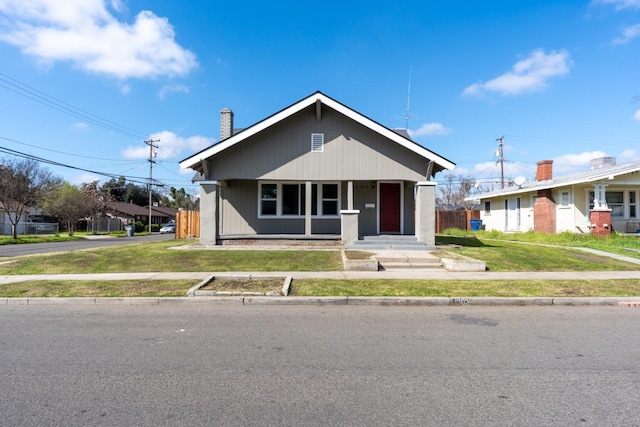 bungalow-style house with a front lawn and fence