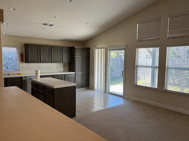 kitchen featuring visible vents, light tile patterned floors, lofted ceiling, light colored carpet, and dishwasher