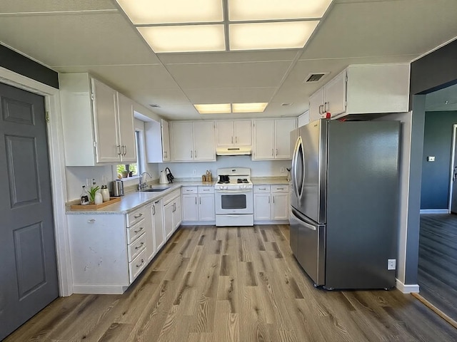 kitchen with visible vents, freestanding refrigerator, white gas stove, under cabinet range hood, and a sink