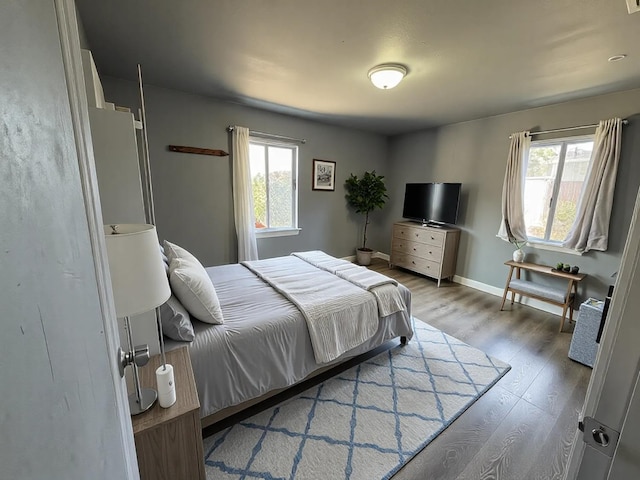 bedroom with multiple windows, baseboards, and wood finished floors