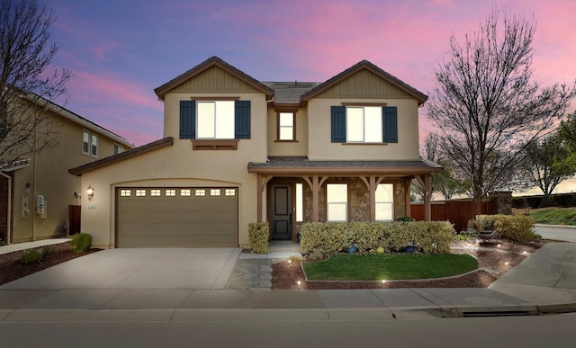 view of front facade with driveway, a garage, fence, and stucco siding