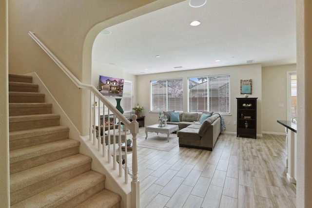 living room featuring recessed lighting, stairs, light wood-style flooring, and baseboards