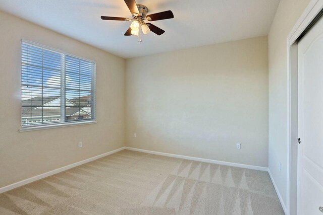 unfurnished bedroom featuring a closet, a ceiling fan, light carpet, and baseboards