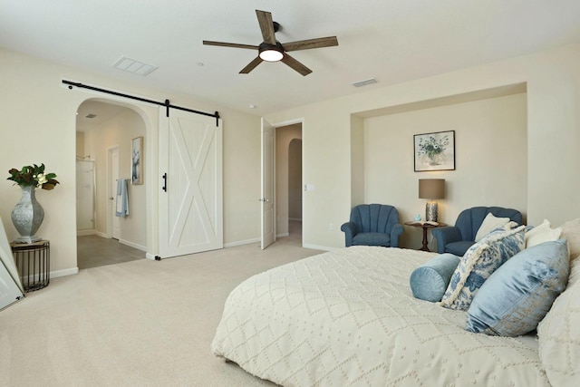 carpeted bedroom featuring arched walkways, visible vents, a barn door, and baseboards