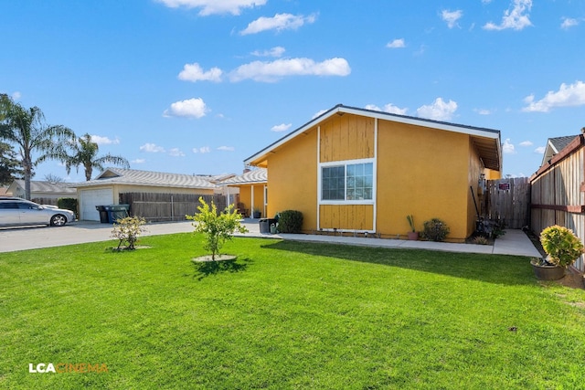 rear view of property featuring a lawn, driveway, and fence