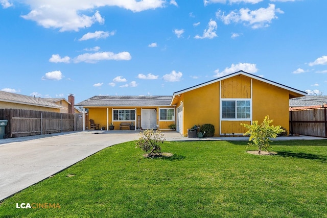 back of property with concrete driveway, a yard, fence, and stucco siding