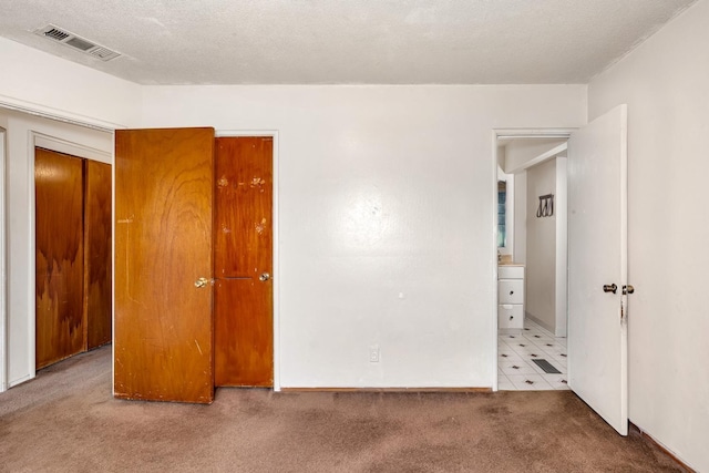 unfurnished bedroom featuring visible vents, carpet floors, and a textured ceiling