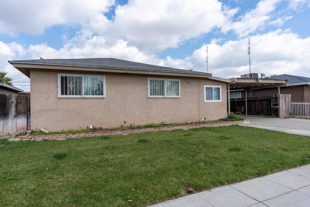 view of front of home featuring fence, stucco siding, a carport, concrete driveway, and a front lawn