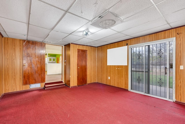 unfurnished room with wooden walls, carpet flooring, and visible vents