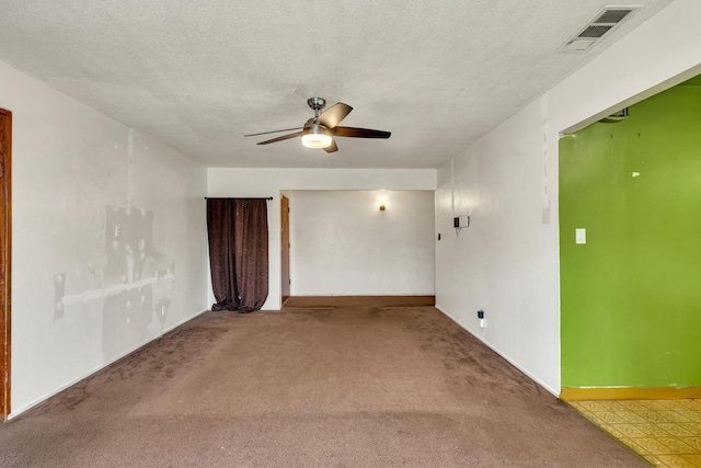 carpeted spare room with visible vents, baseboards, a textured ceiling, and ceiling fan