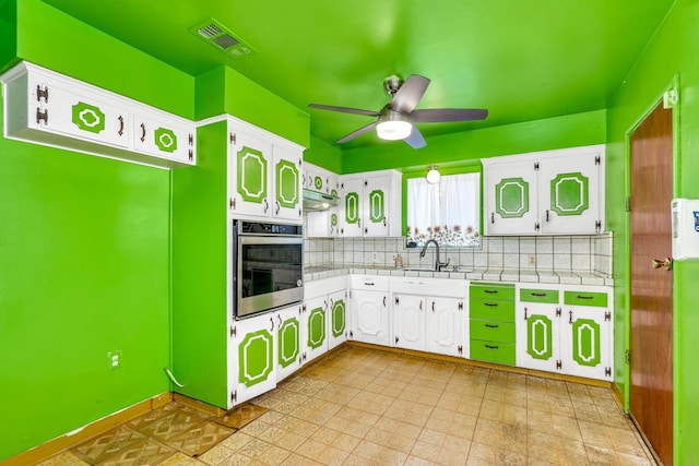 kitchen with visible vents, backsplash, tile countertops, stainless steel oven, and a sink