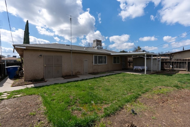 rear view of house with fence, central air condition unit, stucco siding, a lawn, and a patio