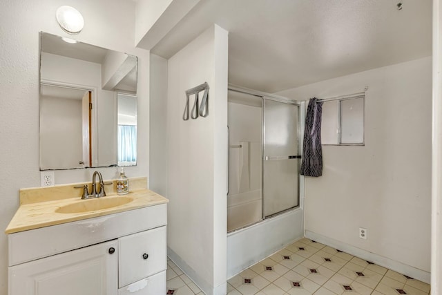 bathroom featuring vanity, baseboards, and shower / bath combination with glass door