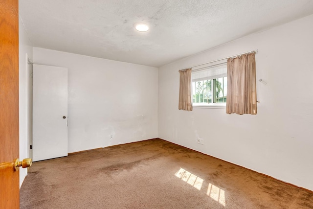 carpeted empty room featuring a textured ceiling