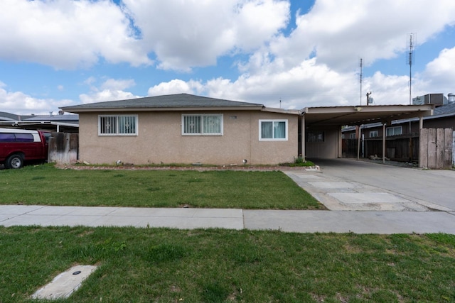 view of front of home with stucco siding, driveway, fence, a front yard, and an attached carport