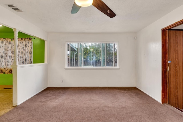 carpeted empty room featuring visible vents, a textured ceiling, and ceiling fan