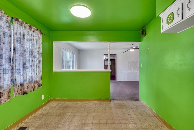 empty room with ceiling fan, light floors, and baseboards