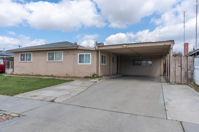 view of front of property featuring a carport, stucco siding, driveway, and a front lawn