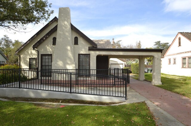 view of front of home featuring stucco siding, a front lawn, fence, roof with shingles, and a chimney